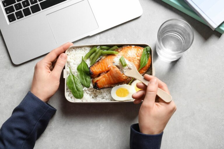 Woman,Eating,Natural,Protein,Food,From,Container,At,Office,Table,